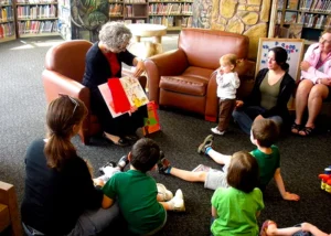 Older woman reading books to children in a library
