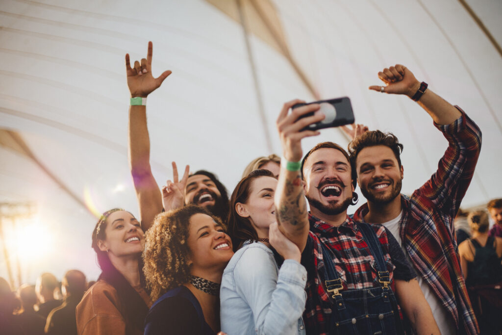 Group of young adult friends take a group selfie on a smartphone at a local event in Springfield, Missouri