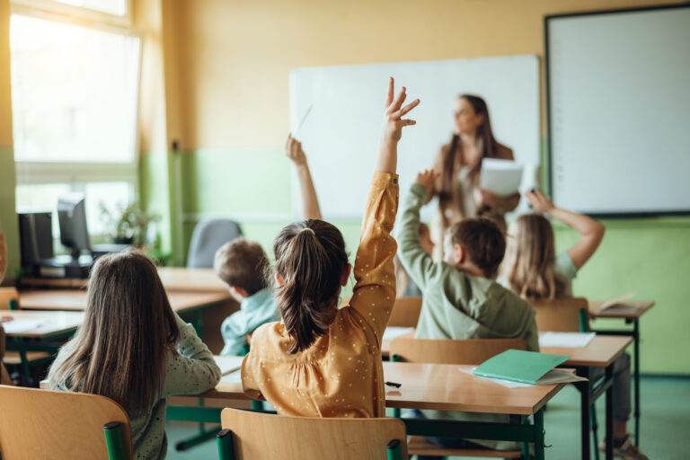 Children raising their hands in class at a school in Springfield, MO