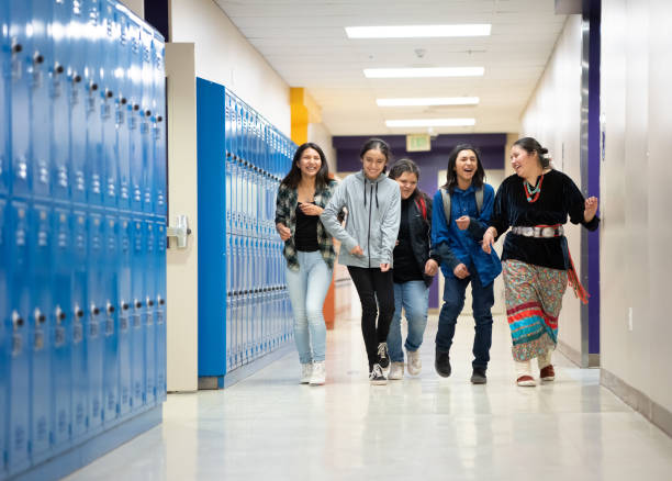 Middle school students walking past lockers in the hallway at school
