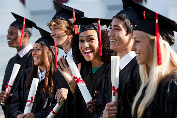 Smiling students with robes and diplomas graduating high school